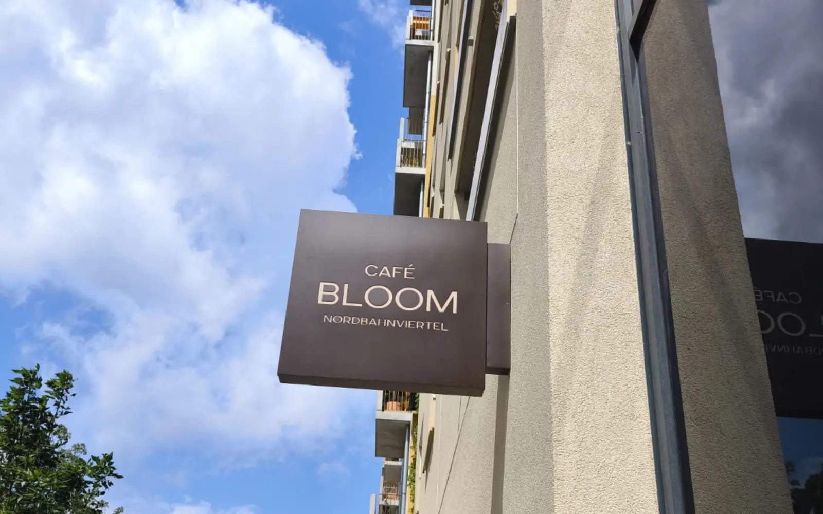 Montiertes Café-Bloom-Fassadenschild am Gebäude